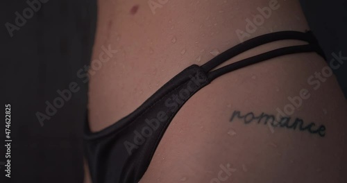 Tattoo of the word romance written on sexy woman with black tanga bikini bottom