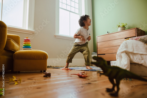 Playful young boy mimicking a t-rex dinosaur at home