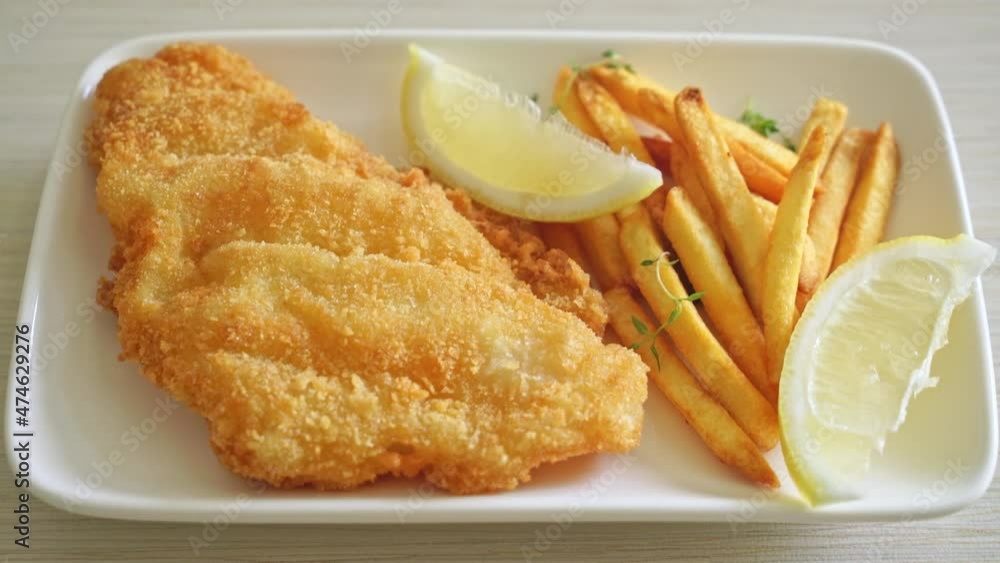 fish and chips - fried fish fillet with potatoes chips and lemon on white plate fish and chips - fried fish fillet with potatoes chips and lemon on white plate