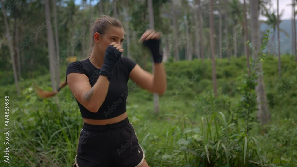 Sporty young woman in black shorts and top shadow boxing outside in the forest health concept Sporty young woman in black shorts and top shadow boxing outside in the forest health concept