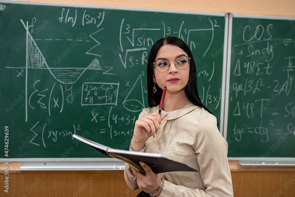 teacher explain completing mathematical equations on chalkboard in classroom teacher explain completing mathematical equations on chalkboard in classroom