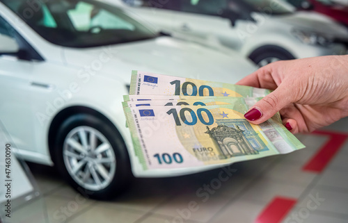 woman holding her hand a large amount of new euro banknotes in the car showroom.