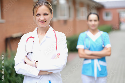 Woman doctor and nurse stand near the clinic