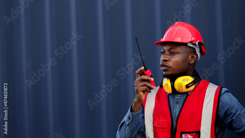 African worker is using walkie talkie in a container yard.