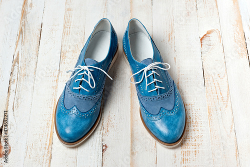 Blue imitation leather shoes laced with white laces. Close-up shot.