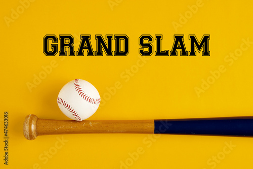 Baseball bat and a ball on yellow background with the word grand slam photo