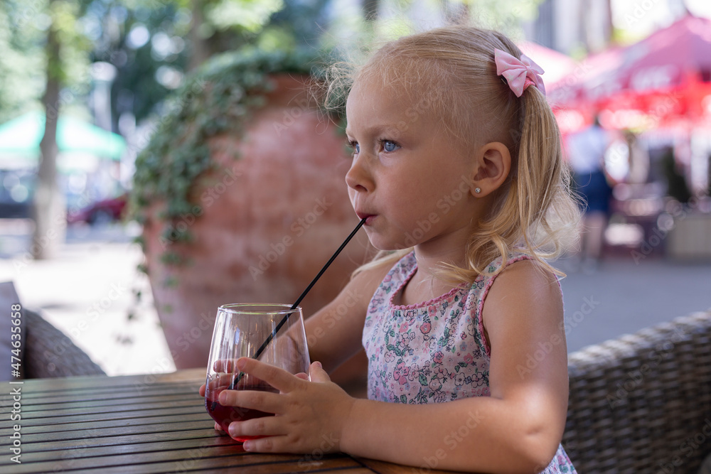 Child drinking a drink on the summer terrace under natural light. Real people Child drinking a drink on the summer terrace under natural light. Real people