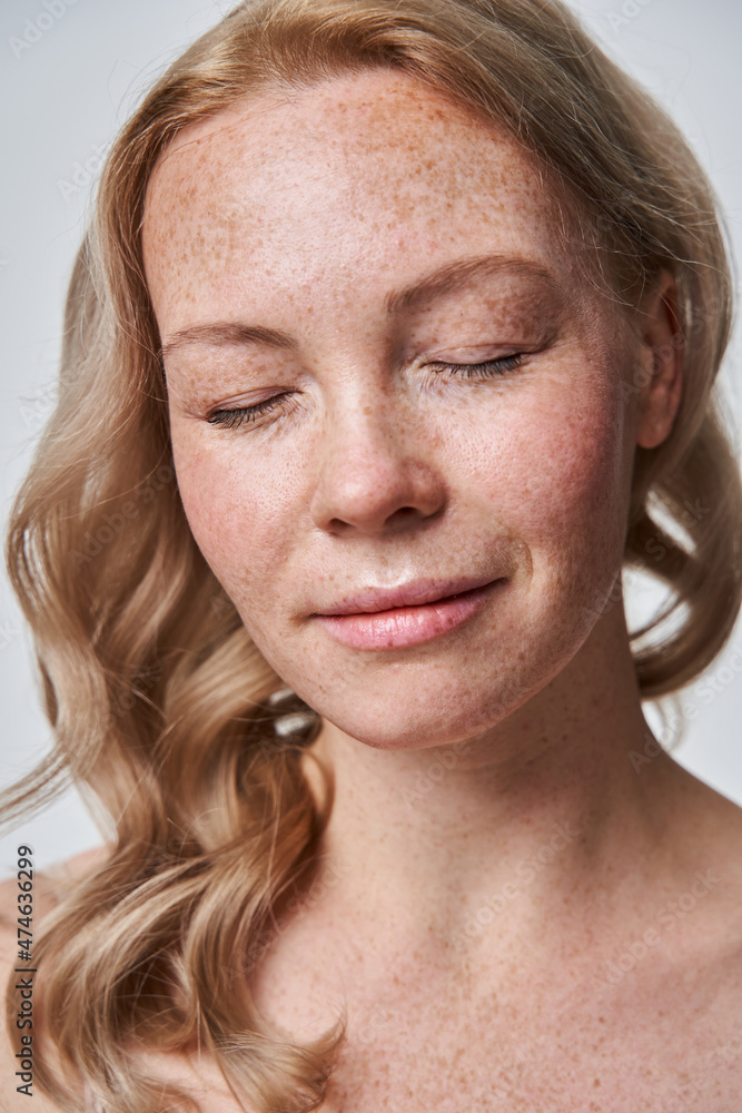 Serene and composed woman closed her eyes with pleasure isolated on white background