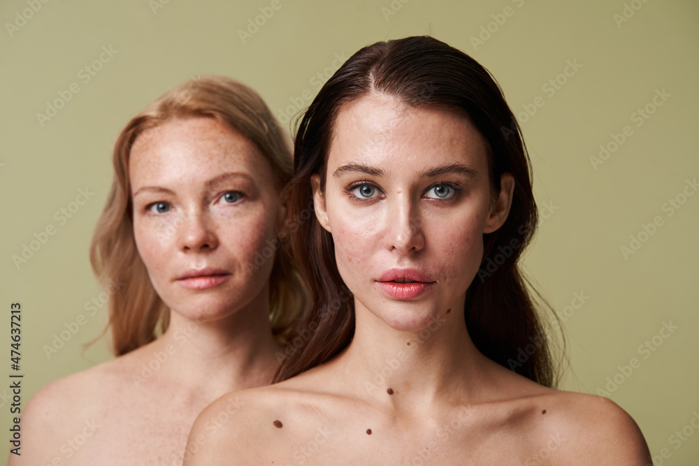 Two diverse women with naked shoulders standing behind of each other Two diverse women with naked shoulders standing behind of each other