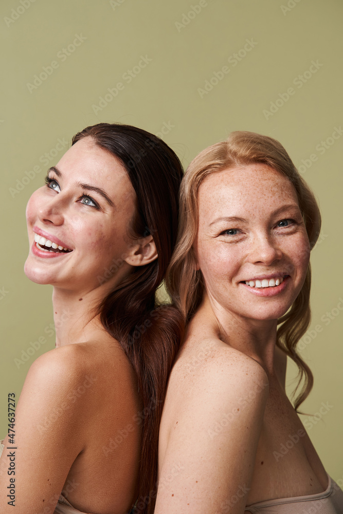 Laughing vivacious diverse women with a beaming smiles posing back to back Laughing vivacious diverse women with a beaming smiles posing back to back