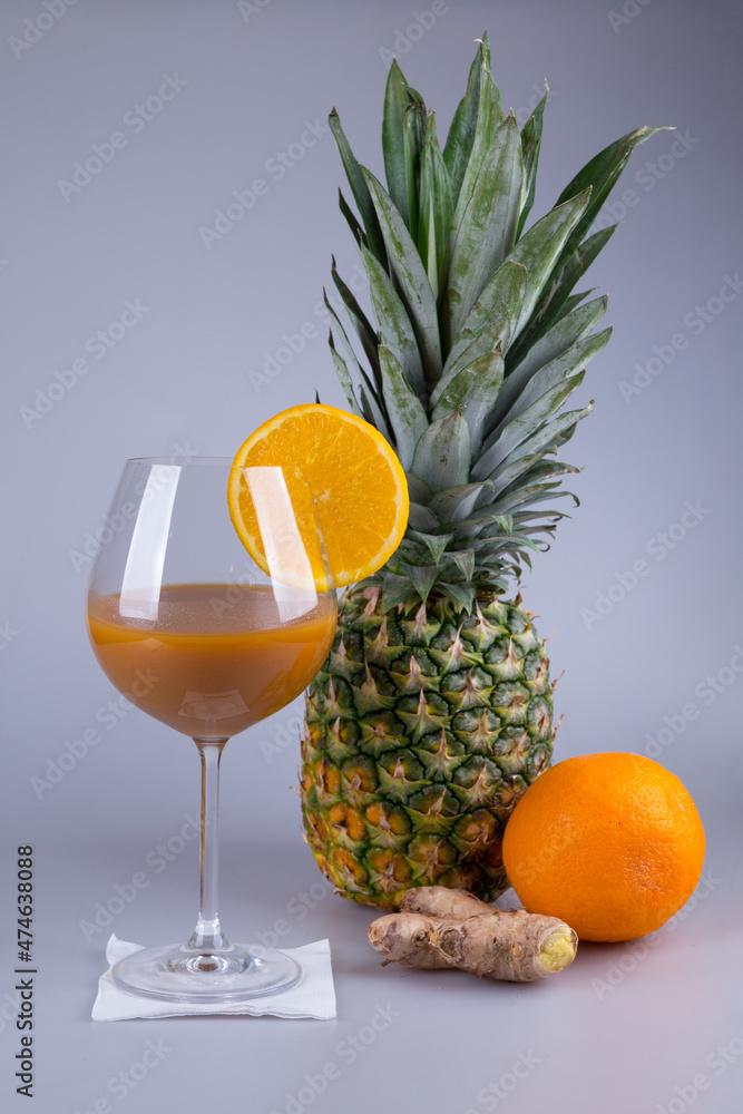 Healthy, fresh pineapple, ginger and orange mixed juice on grey background Healthy, fresh pineapple, ginger and orange mixed juice on grey background