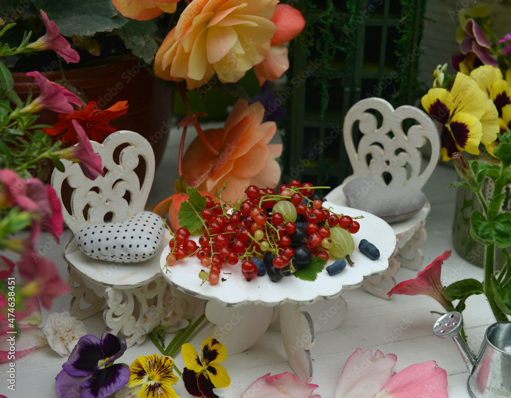 Tiny adorable table and chairs for tea party with flowers and berries.  Fairies in the garden.