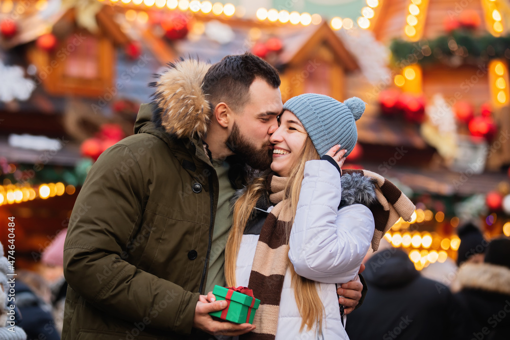 Beautiful couple, boyfriend give a present gift box to a girlfriend  on Christmas fair in Wroclaw, Poland
