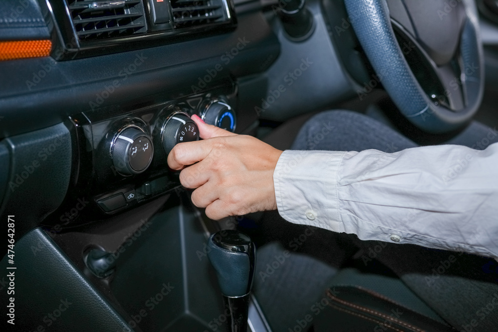 Selective focus, Woman's hand adjusting the cooling level in the car cabin to save energy.