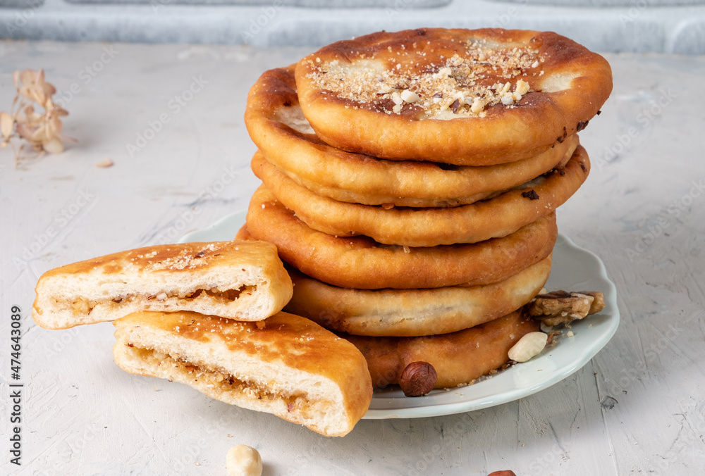 A stack of Korean hotteok dessert on a white table. Fried dough with various fillings.