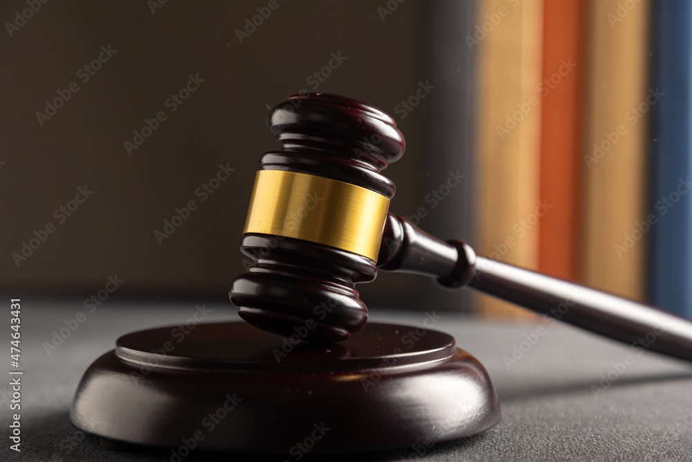 Judge's gavel on a dark background in the library with different books. Law concept Judge's gavel on a dark background in the library with different books. Law concept