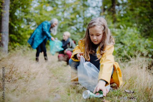 Φωτογραφία Small girl with mother and grandmother picking up waste outoors in forest