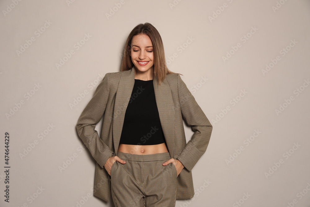 Portrait of beautiful young woman in fashionable suit on grey background. Business attire Portrait of beautiful young woman in fashionable suit on grey background. Business attire