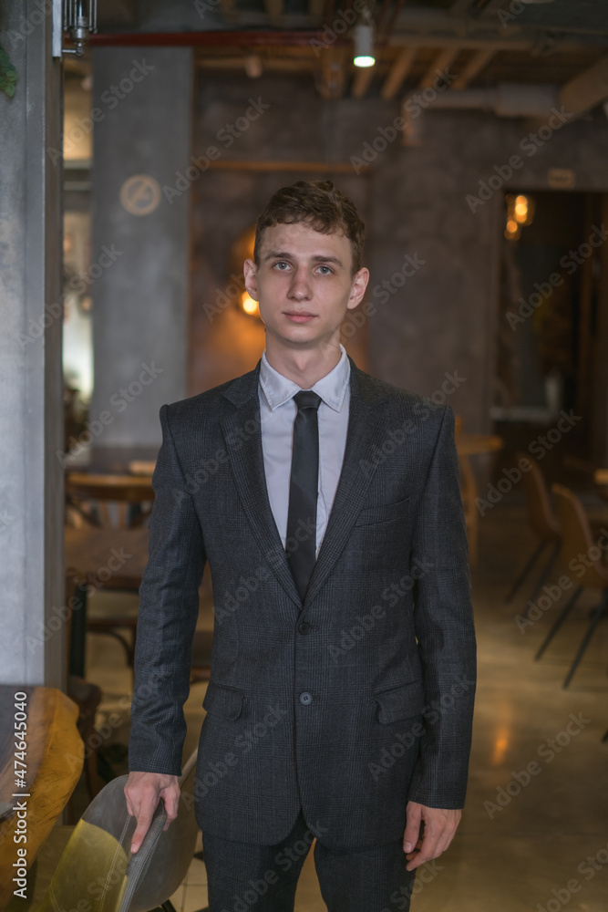 Portrait of young caucasian business man in formal suit standing in the bar. Handsome man standing in the coffee shop and looking at camera 
