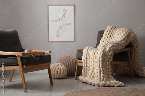 Soft chunky knit blanket on armchair in room. Interior design photo