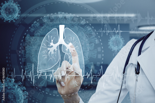 Close up of female doctor pointing at abstract glowing lung interface with virus outline on blurry background. Medicine, pandemic and healthcare concept. Double exposure. photo