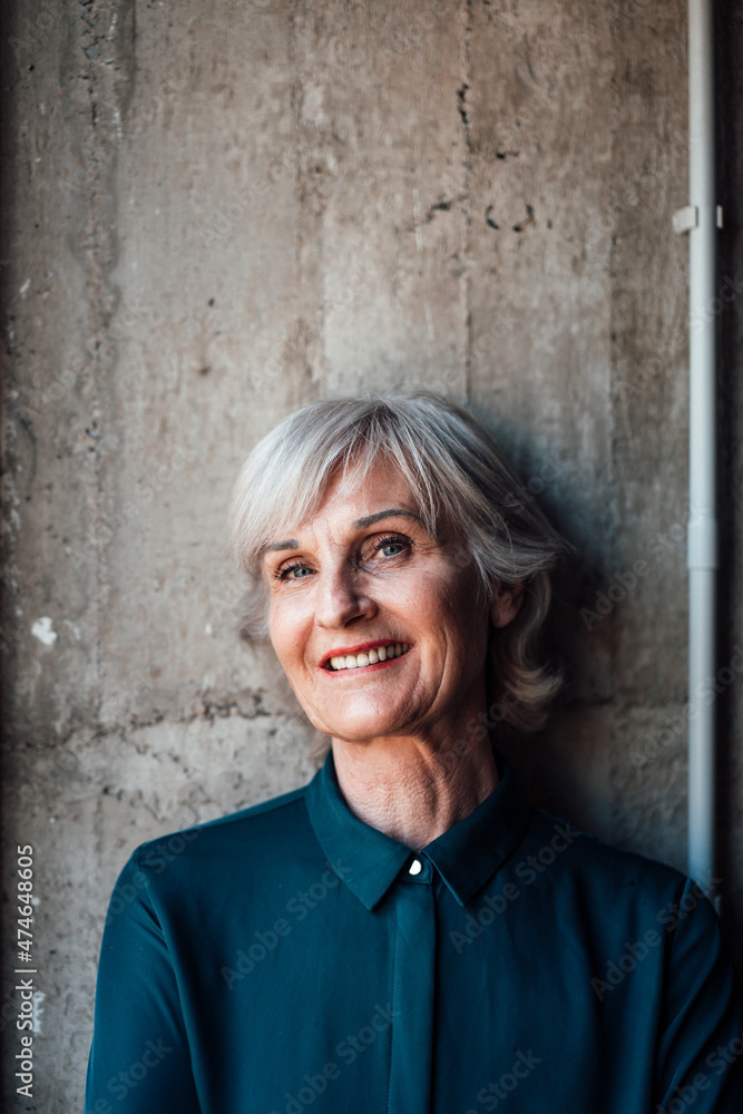 Smiling senior businesswoman in front of wall Smiling senior businesswoman in front of wall