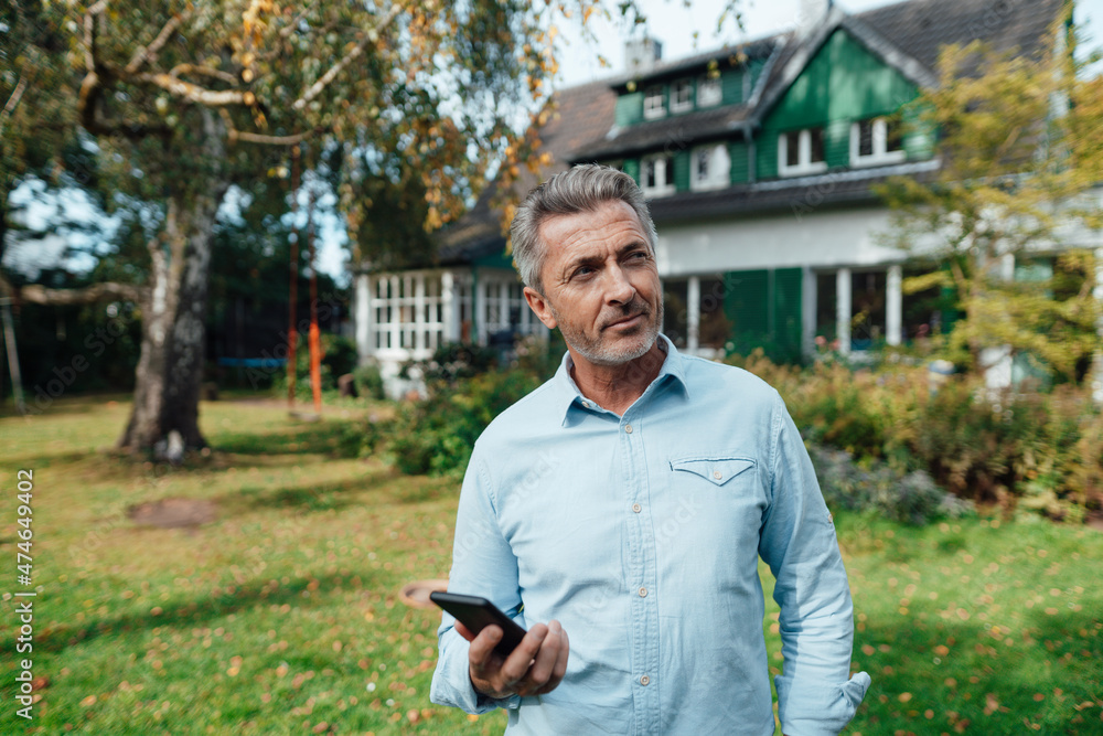 Man holding smart phone at backyard Man holding smart phone at backyard
