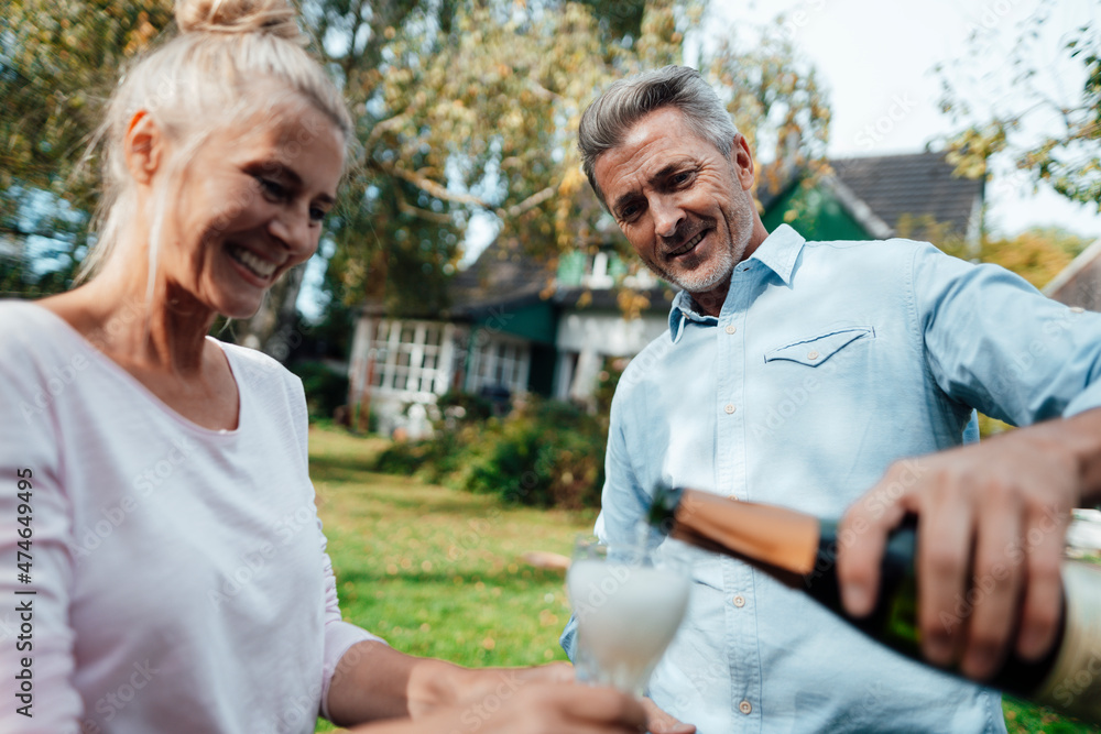 Smiling man pouring champagne in flute for woman at backyard Smiling man pouring champagne in flute for woman at backyard