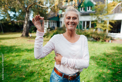 Happy woman holding house key at backyard