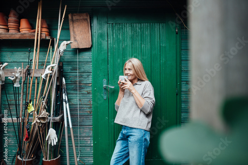 Woman drinking coffee at garden shed entrance