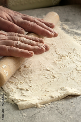Man rolling out a sheet of puff pastry. On a concrete surface