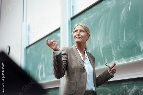 Businesswoman giving presentation by chalkboard at convention center photo