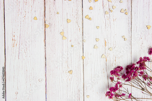 Red flowers with wooden hearts on a wooden background.
