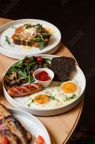 Full english breakfast in a white plate, on the edge of vintage restaurant table, side view