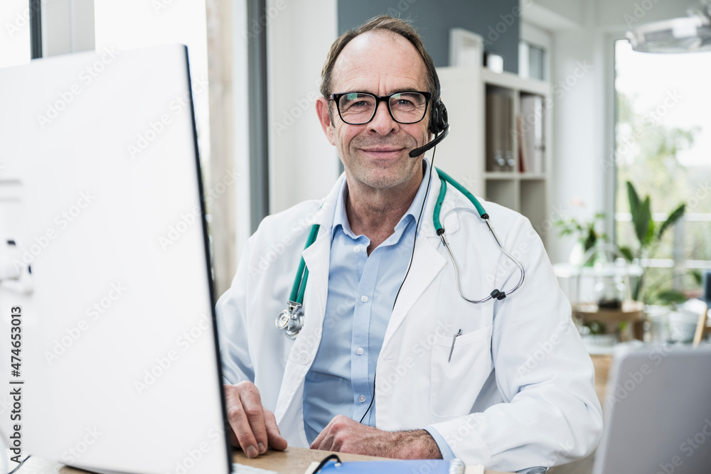 Smiling doctor in front of computer monitor at clinic Smiling doctor in front of computer monitor at clinic