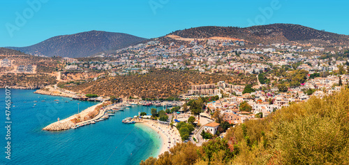 Majestic aerial panoramic view of the seaside resort town Kalkan in Turkey. Romantic lighthouse at entrance to the marina and hotels and villas with orange roofs waiting for tourists photo