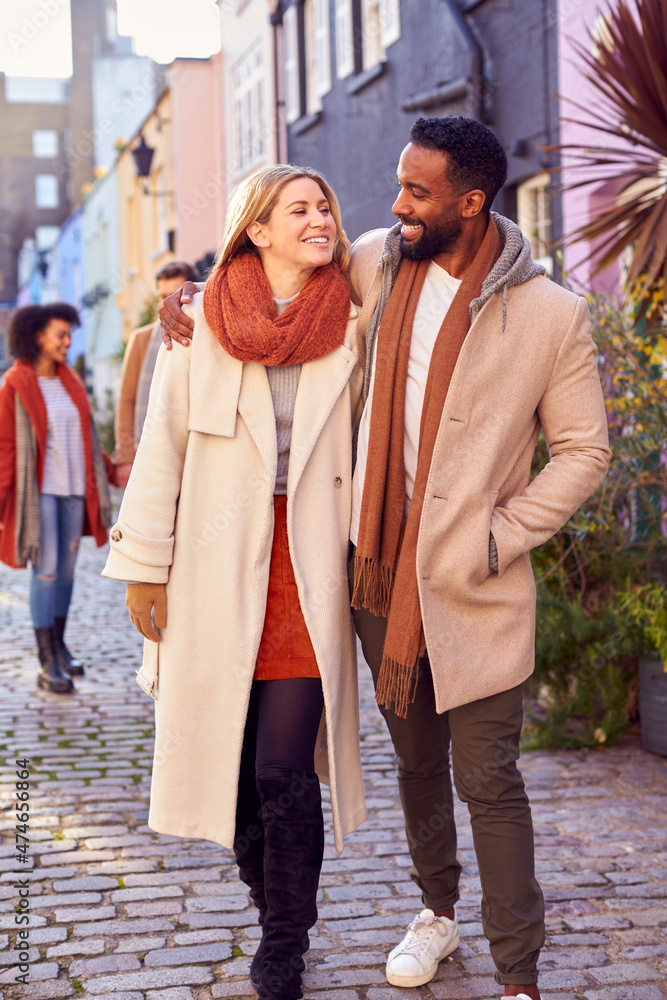 Multi Cultural Couple With Friends Walking Along Residential City Street In Fall Or Winter