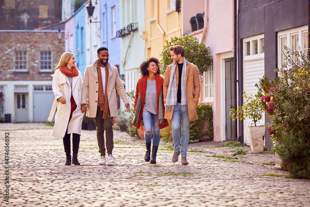 Fototapeta premium Multi Cultural Couple With Friends Walking Along Residential City Street In Fall Or Winter