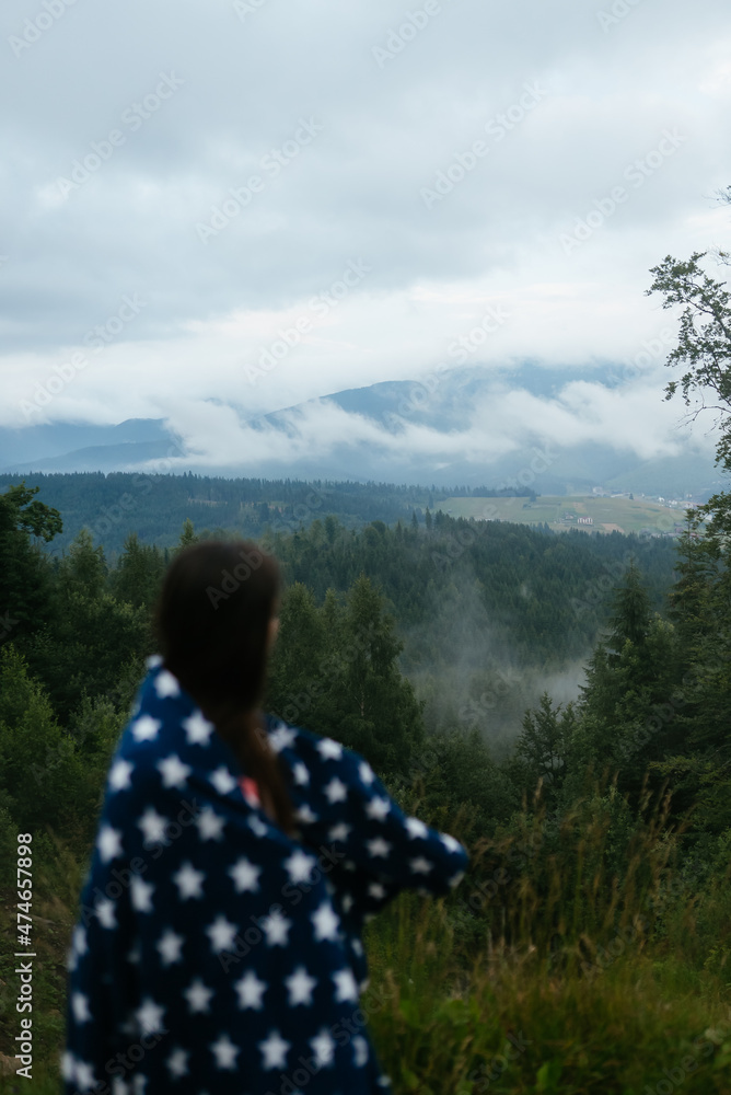 Woman standing on top of a hill, against the background of a valley Woman standing on top of a hill, against the background of a valley