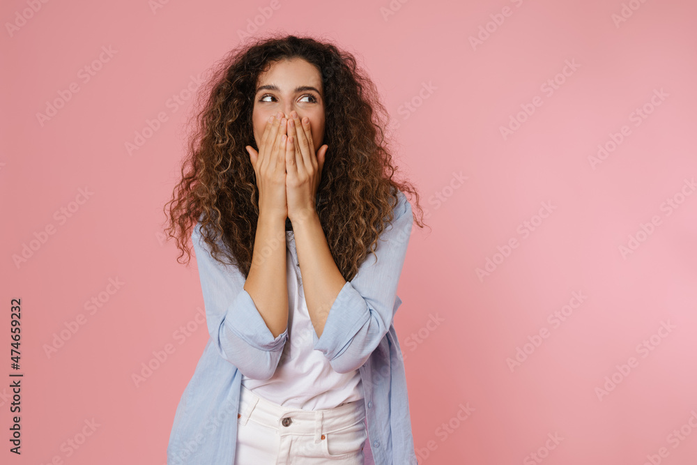 Young brunette woman with wavy hair covering her mouth Young brunette woman with wavy hair covering her mouth
