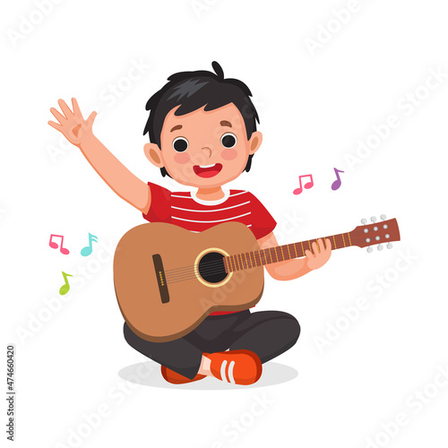 little boy playing guitar and singing sitting on floor waving hand with smiling facial expression
