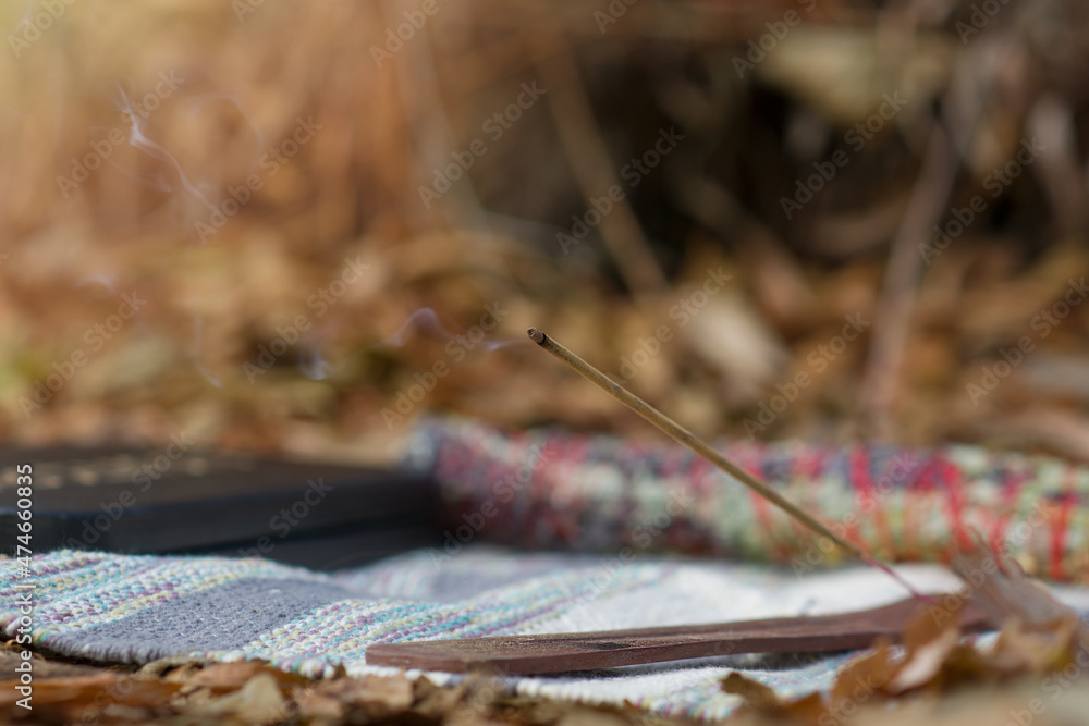 Incense stick with smoke on a stand on a warm autumn day. Set for meditation, yoga, outdoor relaxation exercises. Close-up. Selective focus. Copy space Incense stick with smoke on a stand on a warm autumn day. Set for meditation, yoga, outdoor relaxation exercises. Close-up. Selective focus. Copy space