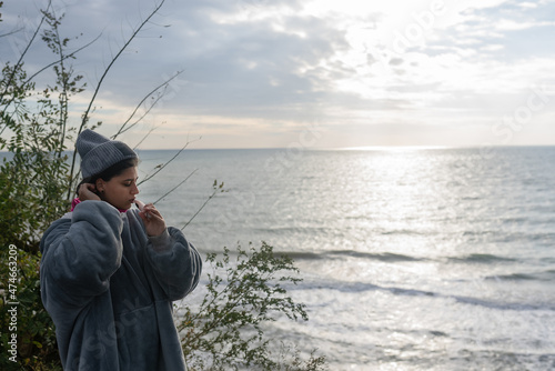 Woman brushing her teeth against the background of the sea sunrise