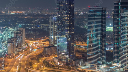 JLT skyscrapers near Sheikh Zayed Road aerial night timelapse. Residential buildings and villas behind © neiezhmakov