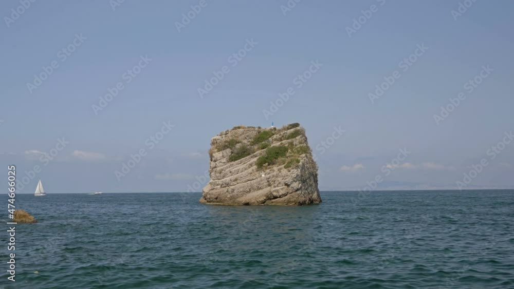 Beautiful lonely rock in the sea. Against the background of blue-green water and blue sky. Beautiful lonely rock in the sea. Against the background of blue-green water and blue sky.