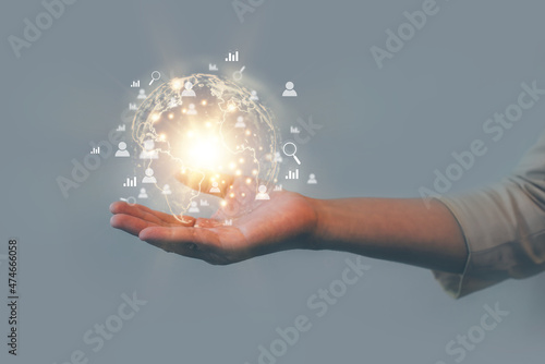 Concept image of a woman's hand holding a connected world on her hand on blue gray background. The modern world where we can meet people who are important anywhere in the world.