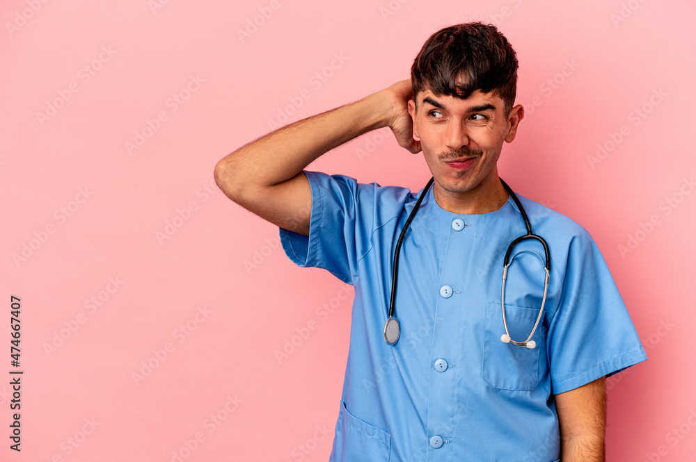 Young mixed race nurse man isolated on pink background touching back of head, thinking and making a choice. Young mixed race nurse man isolated on pink background touching back of head, thinking and making a choice.