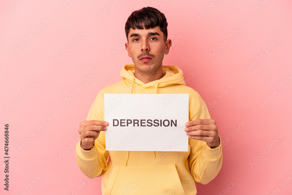 Young mixed race man holding a anxiety placard isolated on pink background Young mixed race man holding a anxiety placard isolated on pink background