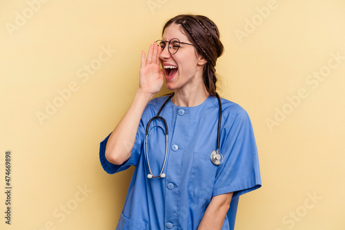 Young nurse caucasian woman isolated on yellow background shouting and holding palm near opened mouth.