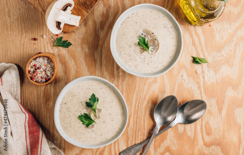 Mushroom cream soup in gray bowls with parsley on wooden background